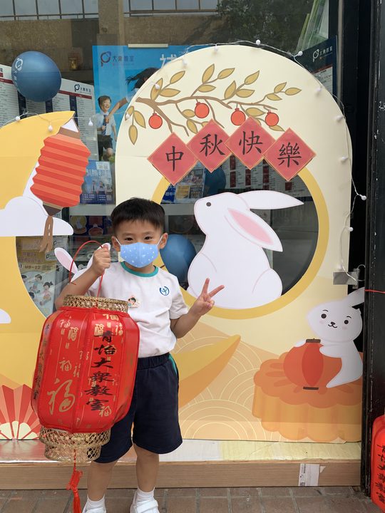 小朋友提着紅色燈籠在月亮兔子背景前留影