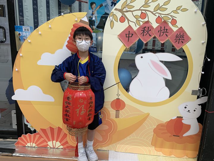 小朋友在中秋布景前提着燈籠